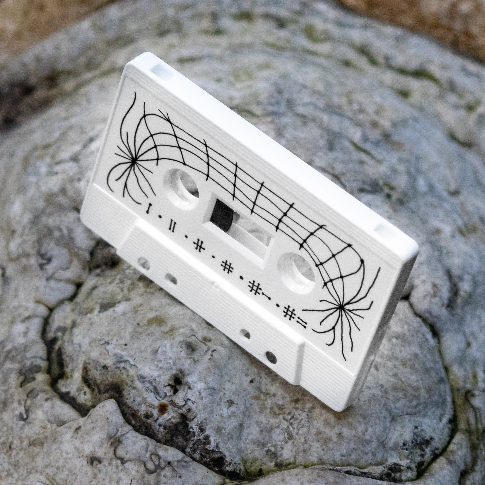 White cassette from the LOM label lying on a rock